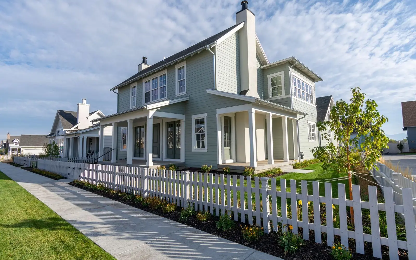 Photo of a new family home with a white picket fence and footpath