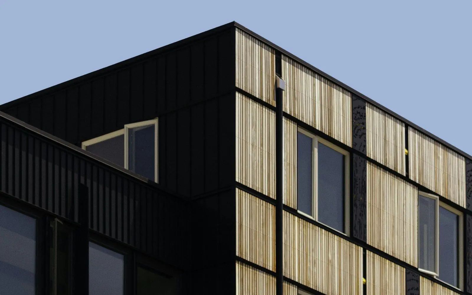A building clad in black metal and vertical timber battens